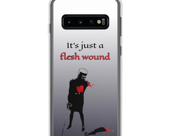 May include: A clear phone case with a black silhouette of a knight with a red heart and a sword. The knight is missing an arm and the text "It's just a flesh wound" is printed on the case.