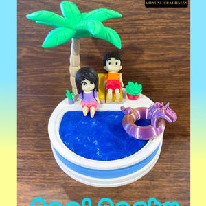 May include: A miniature pool scene with two figurines, a palm tree, and a purple unicorn float. The pool has blue water, and the base is white and blue. The text "Pool Party" is at the bottom.
