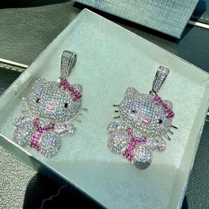 May include: Two silver Hello Kitty pendants with pink bows and rhinestones. The pendants are in a white box with a gray lining.