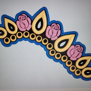 May include: A blue and gold crown with pink roses and a black and gold design. The crown is decorated with a row of gold circles.