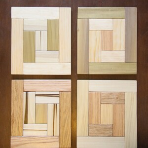 Peut inclure: Quatre sous-verres carrés en bois avec différents motifs de grain de bois. Chaque sous-verre est composé de plusieurs morceaux de bois, créant un design unique.