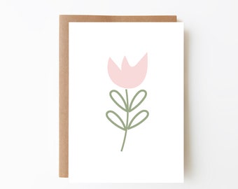 May include: A greeting card with a minimalist floral design. The card features a light pink tulip illustration with green leaves and stem on a white background. The card is set inside a brown envelope.