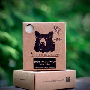May include: A brown cardboard box with a black bear illustration and the text "NORTHERN BEAR SOAP" and "Supernatural Sage 4.5oz - 5.0oz 100% Natural - Free of Synthetics". The box is sitting on top of another brown cardboard box with the text "www.NorthernBearSoap.com".