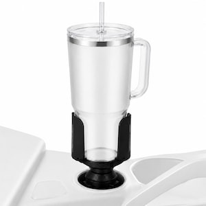 May include: A clear plastic tumbler with a handle, a lid, and a straw, secured within a black adjustable cup holder adapter. The adapter features a circular base designed to fit into a standard vehicle cup holder, providing stability for the drink.