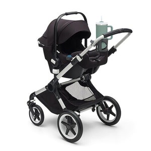 Könnte beinhalten: Ein schwarzer Kinderwagen mit einem schwarzen und silbernen Gestell und einem schwarzen Babysitz. Der Kinderwagen hat einen Getränkehalter mit einem türkisfarbenen Becher.
