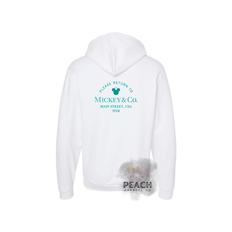 May include: White hooded sweatshirt with a teal blue Mickey Mouse logo and the text "Please return to Mickey & Co. Main Street, USA 1928" printed on the back.