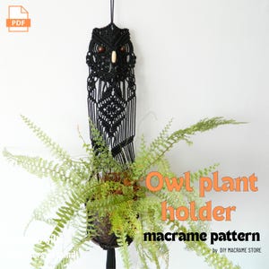 May include: Black macrame owl plant holder with a hanging design. The owl's face features wooden bead eyes and a wooden beak. The plant holder is filled with green leafy plants. Text on the image reads "Owl plant holder macrame pattern".