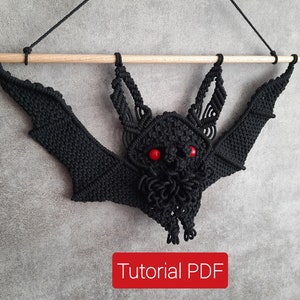 May include: Black macrame bat wall hanging with red bead eyes. The bat is hanging from a wooden dowel rod. Tutorial PDF.