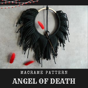 Puede incluir: Colgante de pared de macramé negro con un dije de calavera y flecos. El macramé tiene forma de círculo con una parte inferior puntiaguda. El texto "Angel of Death" está escrito debajo del macramé.