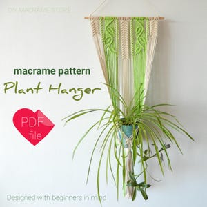Peut inclure: Patron de suspension de plante en macramé, un fichier PDF, avec une suspension de plante en macramé verte et crème accrochée à un mur blanc avec une plante verte dans un pot bleu.