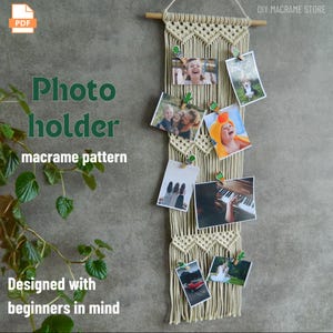 May include: A cream-coloured macrame photo holder with several photos clipped to it. The photos are of various sizes and feature people and places. The text on the holder says "Photo holder macrame pattern Designed with beginners in mind."
