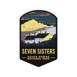 May include: A sticker featuring a landscape illustration of the Seven Sisters cliffs in South Downs National Park. The design includes a row of houses, the cliffs, and the text "SEVEN SISTERS" and "SOUTH DOWNS NATIONAL PARK". The color palette includes shades of blue, yellow, and brown.