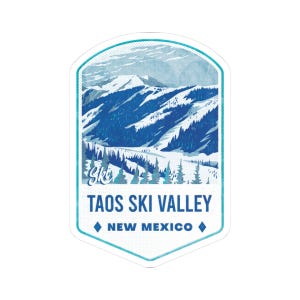 May include: A sticker featuring a blue and white illustration of a mountain range with snow-covered peaks and evergreen trees. The text "TAOS SKI VALLEY NEW MEXICO" is displayed in a white font.