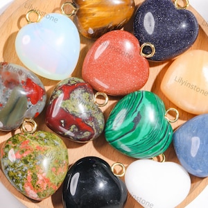 May include: Assortment of heart-shaped gemstone pendants with gold jump rings. The stones include green, red, black, white, blue, brown, and orange.