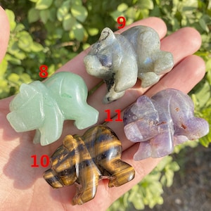Könnte beinhalten: Vier geschnitzte Bärenfiguren aus verschiedenen Steinsorten. Die Bären sind in verschiedenen Posen und mit den Nummern 8, 9, 10 und 11 versehen.