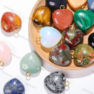 Peut inclure: Assortiment de pendentifs en forme de c&oelig;ur en pierres pr&eacute;cieuses avec des anneaux de saut dor&eacute;s. Les pierres comprennent l'&oelig;il de tigre, le jaspe rouge, l'aventurine verte, l'opale et plus encore.