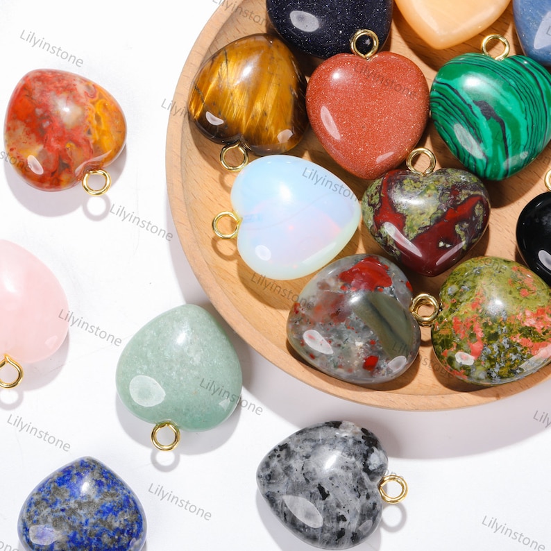 Peut inclure: Assortiment de pendentifs en forme de c&oelig;ur en pierres pr&eacute;cieuses avec des anneaux de saut dor&eacute;s. Les pierres comprennent l'&oelig;il de tigre, le jaspe rouge, l'aventurine verte, l'opale et plus encore.