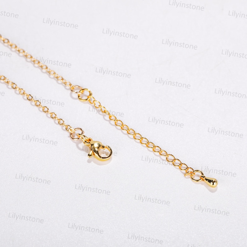 May include: A gold chain necklace with a lobster clasp and a small, round pendant. The chain is made of small, linked circles.