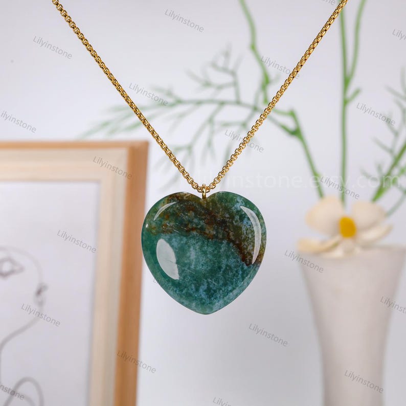 May include: A gold chain necklace with a green heart-shaped pendant. The pendant has a marbled pattern of green, brown, and white.