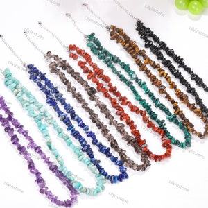 May include: A set of ten necklaces made with various semi-precious stones, including amethyst, turquoise, lapis lazuli, and red jasper. Each necklace is made with small, irregular chips of the stone, creating a unique and natural look.
