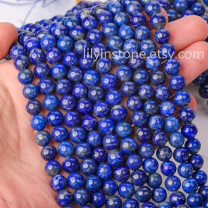 Può includere: Una collana di perle rotonde in lapislazzuli blu scuro. Le perle sono lisce e lucidate. Le perle sono infilate su un filo elastico trasparente.