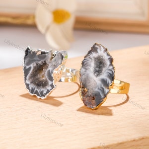 Puede incluir: Dos anillos de ágata con engastes de oro y plata. Los anillos presentan una piedra de ágata natural con un diseño de cueva de cristal. La ágata es de color gris claro con remolinos negros y blancos.