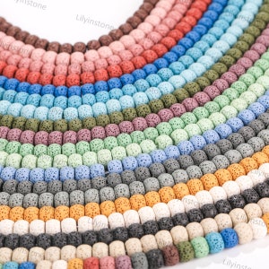 May include: A variety of colors of lava rock beads, arranged in rows. The beads are round and have a rough, porous texture.