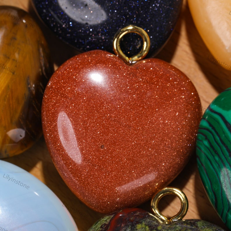 Peut inclure: Un pendentif en forme de c&oelig;ur en pierre rouge avec une b&eacute;li&egrave;re en or. La pierre pr&eacute;cieuse a une texture scintillante et chatoyante.