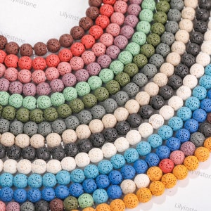 May include: A variety of lava rock beads in different colors, including white, black, blue, green, orange, and red. The beads are round and have a porous texture.
