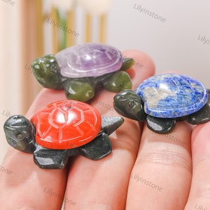 May include: Three small turtle figurines carved from green stone with different coloured gemstone tops. The turtles are red, purple and blue.