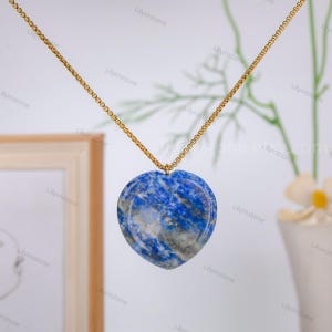 May include: A gold chain necklace with a heart-shaped pendant made of blue lapis lazuli stone.