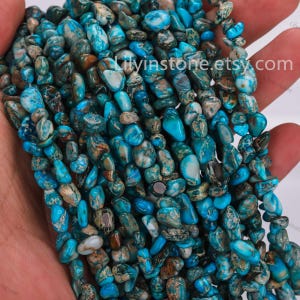 Puede incluir: Una hebra de cuentas de jaspe chip de color turquesa y marrón. Las cuentas tienen una forma irregular y un acabado natural y pulido.