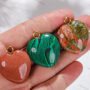 Peut inclure: Trois pendentifs en forme de c&oelig;ur en pierre de diff&eacute;rentes couleurs. Les pendentifs sont vert, rouge et marron. Chaque pendentif a une boucle dor&eacute;e en haut pour l'attacher &agrave; une cha&icirc;ne ou un cordon.