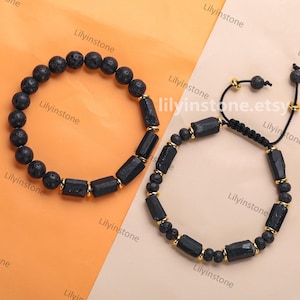 May include: Two black beaded bracelets with gold accents. One bracelet is made of black lava rock beads and the other is made of black obsidian beads.