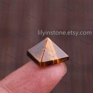 Peut inclure: Un petit cristal de pyramide en &oelig;il de tigre brun dor&eacute;. La pyramide est pos&eacute;e sur un doigt.