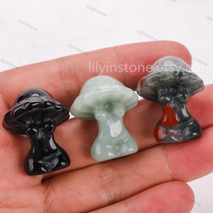 Peut inclure: Trois petites sculptures en forme de champignon faites de différents types de pierre. La première est noire, la deuxième est verte et la troisième est un mélange de rouge, noir et vert.