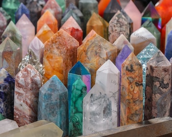 May include: A collection of colorful crystal points arranged in a row on a wooden surface. The points are made of various types of crystals, including amethyst, rose quartz, clear quartz, and citrine.
