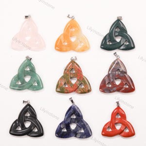 May include: Nine gemstone pendants in a Celtic knot design. The pendants are in various colors, including pink, orange, green, red, and blue. Each pendant has a silver-colored bail at the top for attaching to a chain.