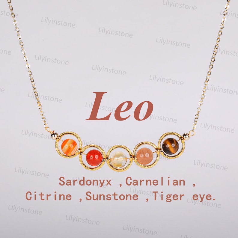May include: Gold necklace with a charm featuring six different colored stones. The stones are labeled as Sardonyx, Carnelian, Citrine, Sunstone, and Tiger eye. The word "Leo" is written in red above the charm.
