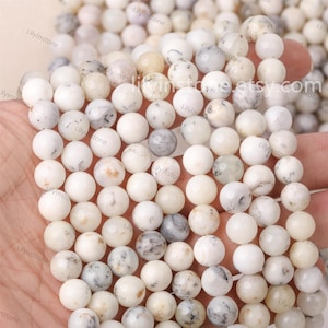 May include: A strand of white and gray round beads with a speckled pattern. The beads are approximately 8mm in diameter.