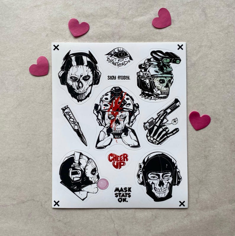 Puede incluir: Una hoja de pegatinas con ilustraciones en blanco y negro de personajes con calaveras, equipo t&aacute;ctico y armas. El texto incluye "STAY FROSTY", "GHOST", "CHEER UP" y "MASK STAYS ON". Los dise&ntilde;os est&aacute;n detallados con l&iacute;neas de tinta de alto contraste.