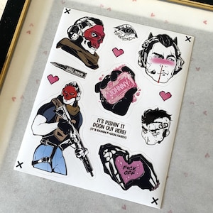 Puede incluir: Una hoja de pegatinas con varias ilustraciones, incluyendo un personaje con m&aacute;scara de calavera roja, una bala con la etiqueta SKILL ISSUE, una mano sosteniendo una pastilla de jab&oacute;n con la etiqueta JOHNNY, un personaje con auriculares y el texto IT'S PISHIN' IT DOON OUT HERE!