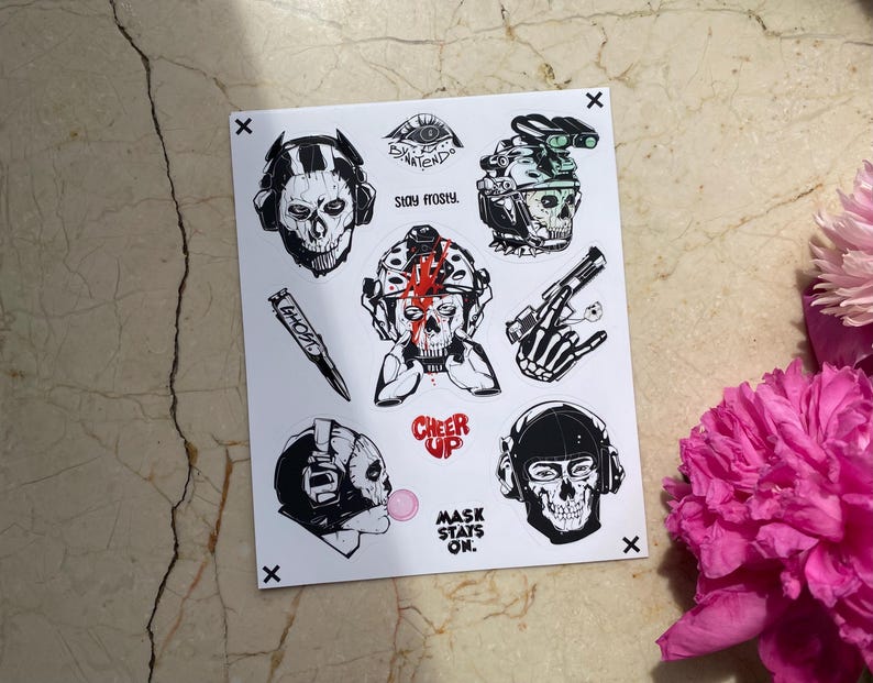 Puede incluir: Una hoja de pegatinas blanca con ilustraciones en blanco y negro de personajes con m&aacute;scaras de calavera y equipo t&aacute;ctico. Los dise&ntilde;os incluyen una bala con la etiqueta GHOST, textos como STAY FROSTY, CHEER UP, MASK STAYS ON y una burbuja rosa.