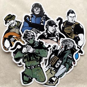 Könnte beinhalten: Eine Sammlung von Aufklebern mit Illustrationen von Soldaten, die jeweils eine Katze halten. Die Soldaten sind in taktischer Ausrüstung dargestellt, und die Katzen haben unterschiedliche Farben. Die Aufkleber haben einen weißen Rand.