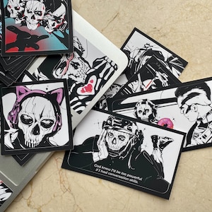 Puede incluir: Una colección de pegatinas rectangulares con ilustraciones en blanco y negro de personajes con máscaras de calavera. Una pegatina muestra a un personaje con orejas de gato rosas, mientras que otra incluye el texto, God knew I'd be too powerful if I had conversation skills.