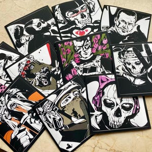 K&ouml;nnte beinhalten: Eine Sammlung quadratischer Kunstdrucke mit schwarz-wei&szlig;en grafischen Illustrationen von Charakteren in taktischer Ausr&uuml;stung und Totenkopfmasken. Einige Drucke enthalten Akzente in Pink, Orange und Rot. Ein Druck zeigt ein pinkes Telefon mit dem Text CALL ME.