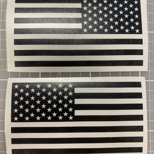 May include: Two black and white American flag decals. The flags are printed on a white background with black stripes and white stars.