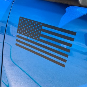 May include: A black and white American flag decal on a blue car.