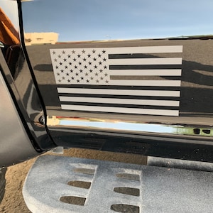 May include: A black truck with a white American flag decal on the side. The flag is a simple design with white stars and stripes.