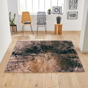 May include: A brown and black area rug with a tree trunk design. The rug has a circular pattern that resembles the rings of a tree trunk.